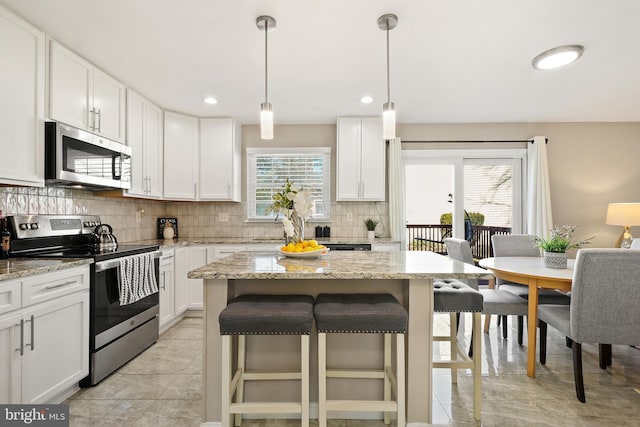 kitchen with tasteful backsplash, appliances with stainless steel finishes, a breakfast bar area, and white cabinets