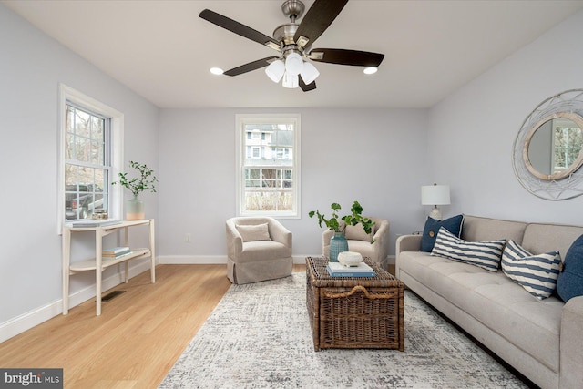 living area featuring plenty of natural light, baseboards, ceiling fan, and wood finished floors