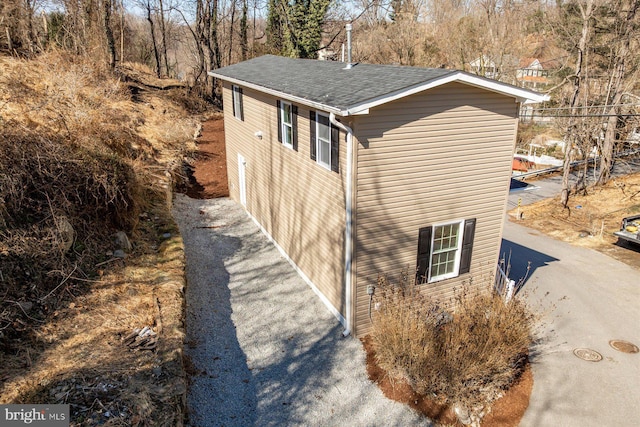 view of side of home with roof with shingles