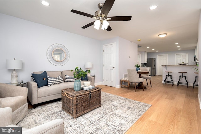 living area with baseboards, ceiling fan, light wood finished floors, and recessed lighting