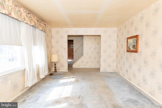 empty room featuring baseboards, carpet, stairs, and wallpapered walls