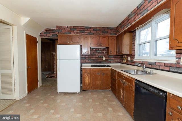 kitchen featuring a sink, brick wall, dishwasher, and freestanding refrigerator