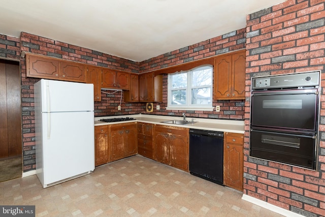 kitchen featuring black appliances, brown cabinets, a sink, and light floors