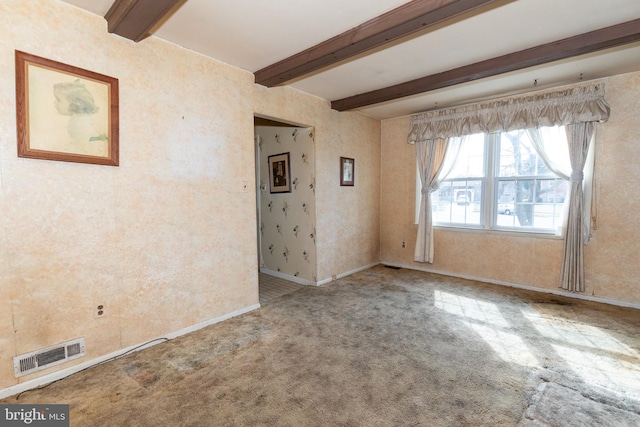 spare room featuring carpet floors, beam ceiling, visible vents, and baseboards