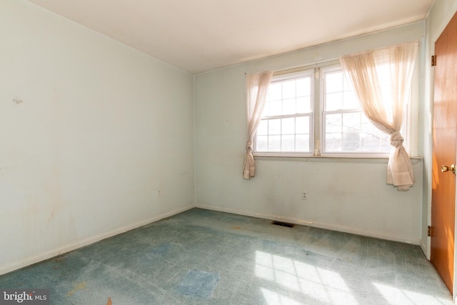 carpeted empty room featuring baseboards and visible vents