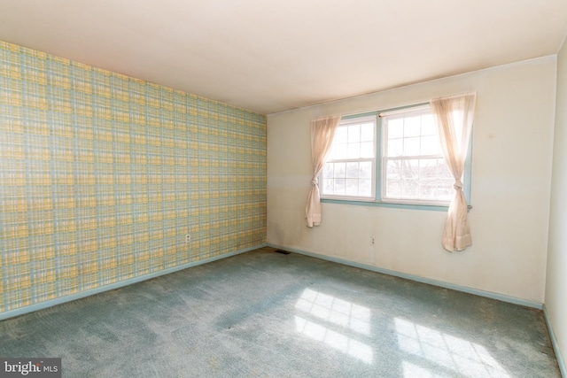 carpeted spare room featuring wallpapered walls, an accent wall, and baseboards