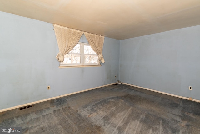 carpeted spare room with baseboards, visible vents, and vaulted ceiling