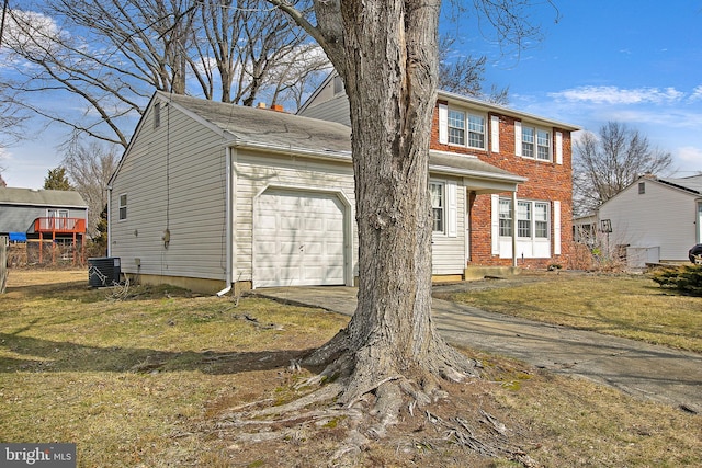 view of front facade featuring a front yard, concrete driveway, brick siding, and an attached garage