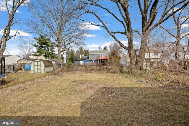 view of yard featuring an outbuilding, a storage unit, a trampoline, and fence