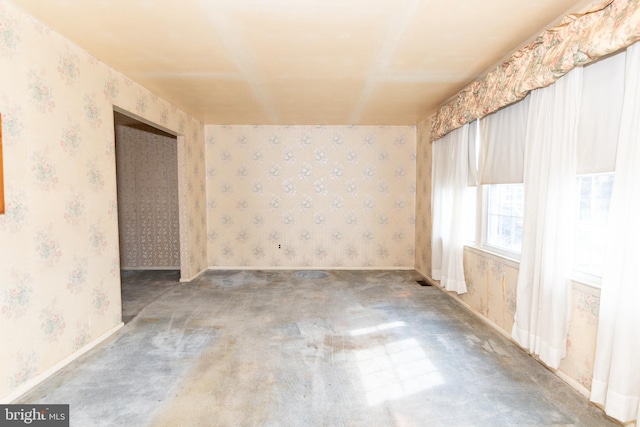 carpeted spare room featuring baseboards and wallpapered walls