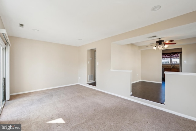 carpeted spare room featuring visible vents, baseboards, and a ceiling fan