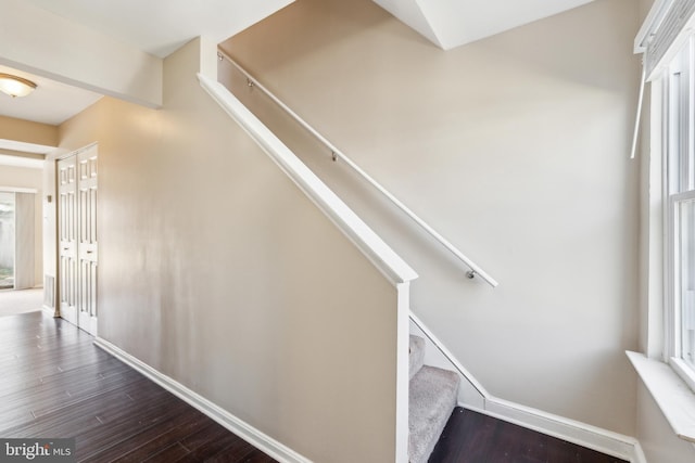 stairs with plenty of natural light, wood finished floors, and baseboards