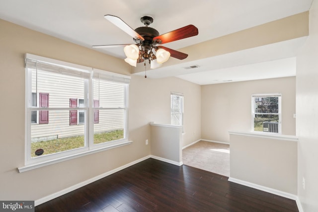 spare room with a wealth of natural light, visible vents, dark wood-type flooring, and baseboards