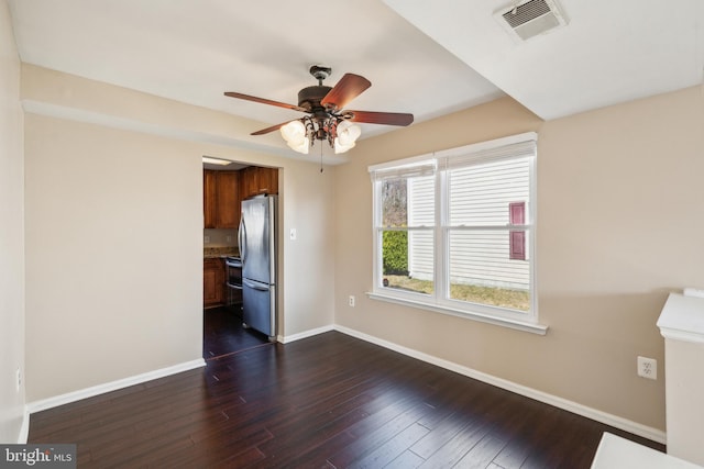 unfurnished room featuring dark wood-style floors, visible vents, a ceiling fan, and baseboards