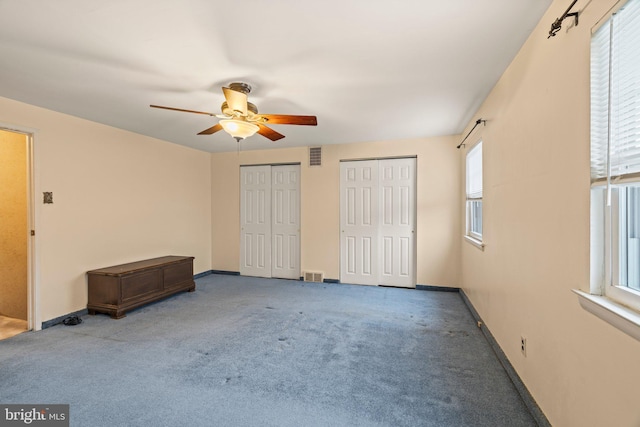 unfurnished bedroom featuring carpet flooring, visible vents, multiple closets, and baseboards