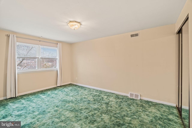 empty room with carpet flooring, baseboards, and visible vents