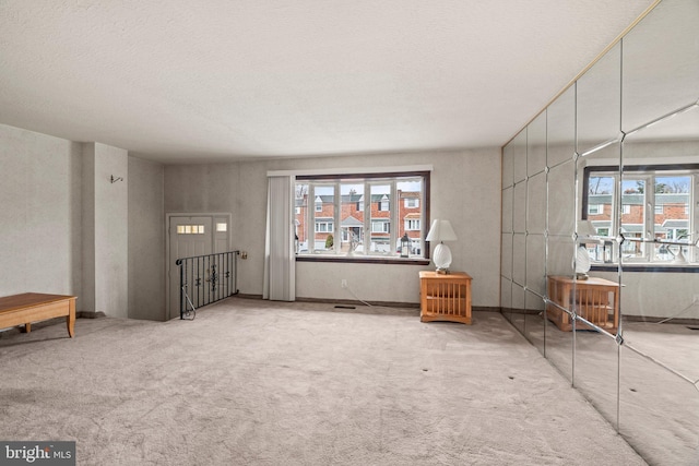 unfurnished living room featuring a textured ceiling and carpet floors