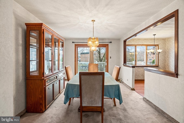 dining area featuring a chandelier, light colored carpet, a textured ceiling, and a textured wall