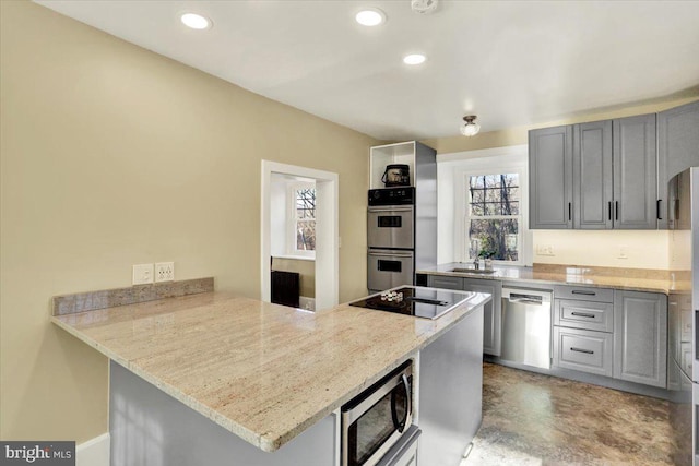 kitchen with gray cabinets, a sink, recessed lighting, appliances with stainless steel finishes, and a peninsula