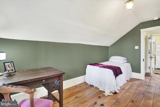 bedroom with baseboards, lofted ceiling, and hardwood / wood-style floors