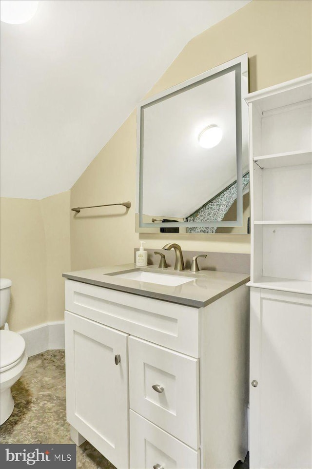 half bath with toilet, vanity, baseboards, and vaulted ceiling