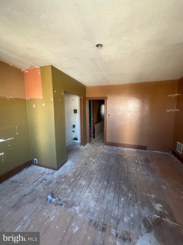 unfurnished room featuring visible vents, a textured ceiling, and hardwood / wood-style floors