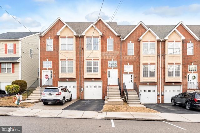 multi unit property featuring a garage, brick siding, and driveway