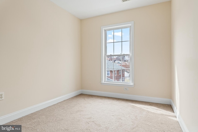 carpeted spare room featuring plenty of natural light, visible vents, and baseboards