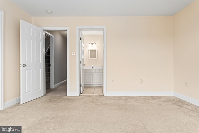 unfurnished bedroom featuring light colored carpet, connected bathroom, and baseboards