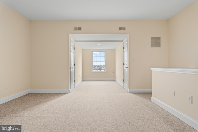 empty room featuring baseboards, visible vents, and light colored carpet