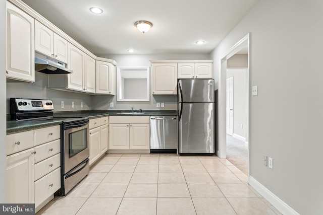 kitchen featuring light tile patterned floors, under cabinet range hood, a sink, appliances with stainless steel finishes, and dark countertops