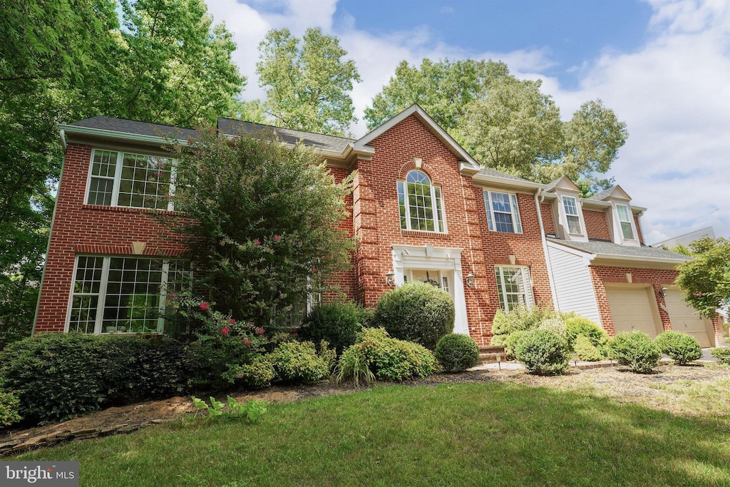 colonial inspired home with brick siding and a front lawn