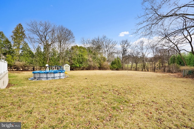 view of yard featuring a storage unit, an outdoor structure, and an outdoor pool