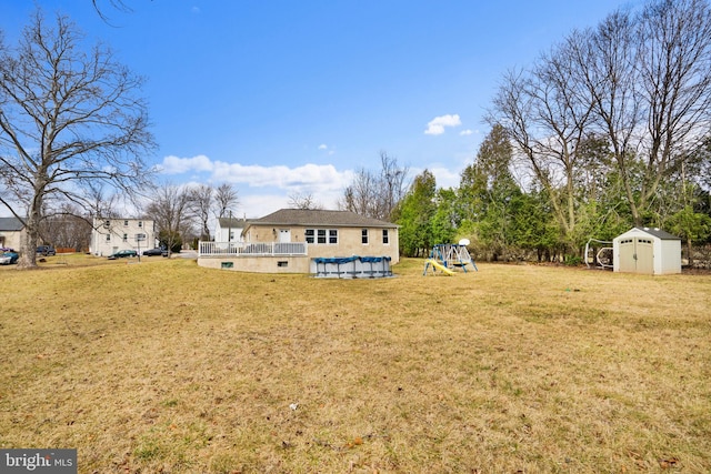 view of yard with an outbuilding, a shed, a playground, and a covered pool