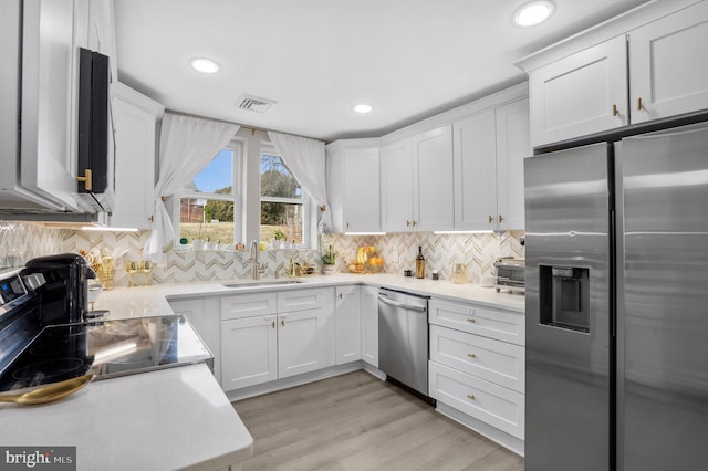 kitchen featuring light countertops, visible vents, appliances with stainless steel finishes, white cabinets, and a sink