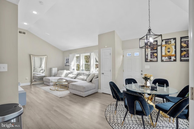 dining area with lofted ceiling, visible vents, a chandelier, and wood finished floors