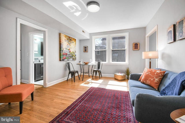 living area with light wood finished floors, visible vents, and baseboards