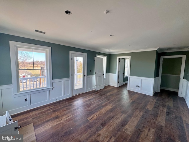 unfurnished bedroom featuring dark wood-style flooring, a wainscoted wall, crown molding, visible vents, and access to outside