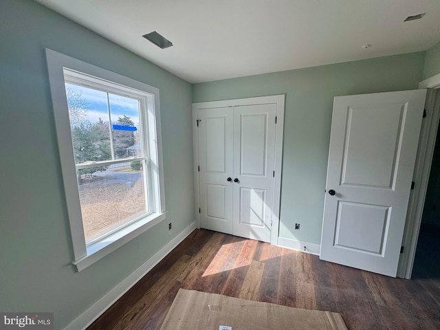 unfurnished bedroom with a closet, baseboards, and wood finished floors