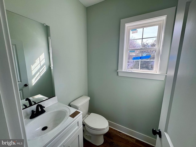 bathroom with baseboards, vanity, toilet, and wood finished floors