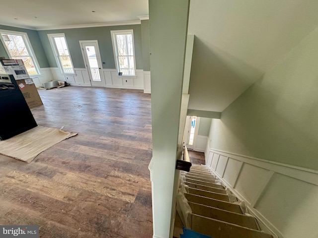 stairway with ornamental molding, wainscoting, and wood finished floors