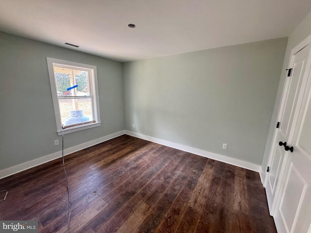 unfurnished bedroom featuring dark wood-style flooring, visible vents, and baseboards