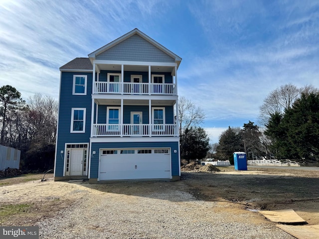 beach home featuring an attached garage, a balcony, and dirt driveway