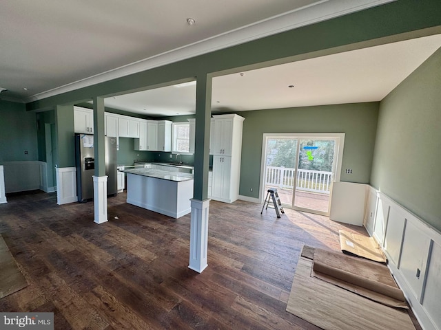 kitchen with white cabinets, a wainscoted wall, dark wood-style flooring, a center island, and stainless steel refrigerator with ice dispenser