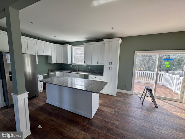 kitchen with dark wood finished floors, a center island, freestanding refrigerator, white cabinetry, and a sink