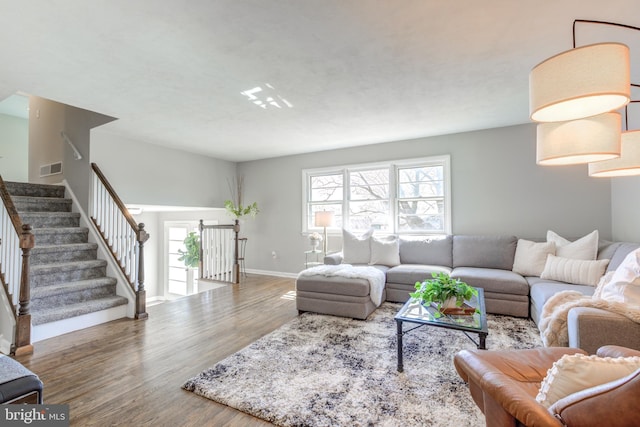 living room with stairway, baseboards, and wood finished floors