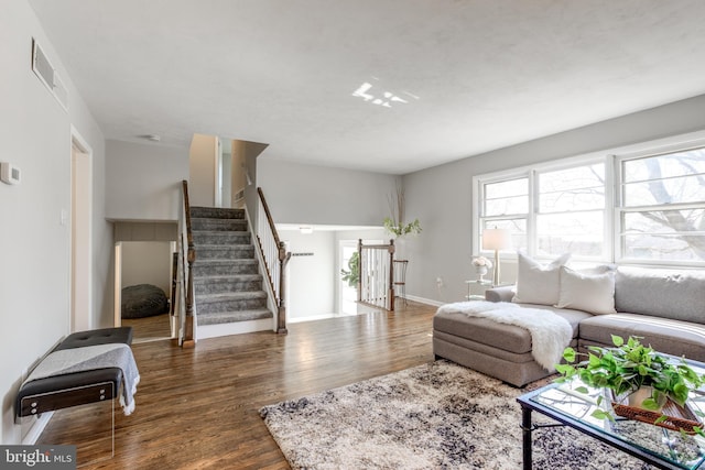 living room with visible vents, stairs, baseboards, and wood finished floors