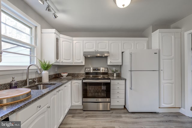 kitchen featuring under cabinet range hood, stainless steel electric stove, freestanding refrigerator, white cabinetry, and a sink