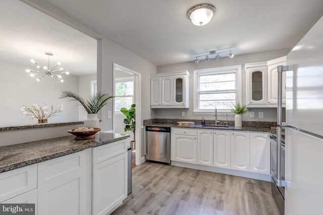 kitchen featuring glass insert cabinets, stainless steel dishwasher, freestanding refrigerator, white cabinets, and a sink