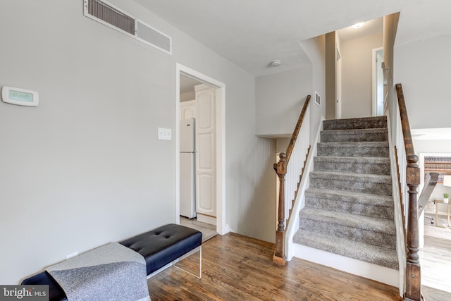 stairs with visible vents and wood finished floors